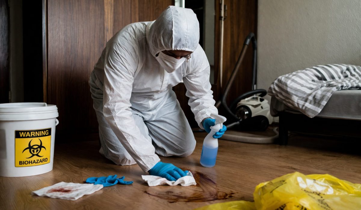 Expert en tenue de protection nettoyant une pièce après décès avec matériel de désinfection
